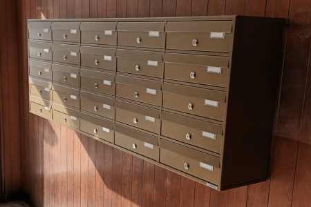 Cassette postali condominiali da interno installate su parete in legno a Torino.